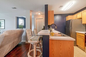 A modern kitchen with a central island, wooden cabinets, and a built-in refrigerator. - Murrells Inlet Condo: Close to Beaches, Amenities (Murrells Inlet)