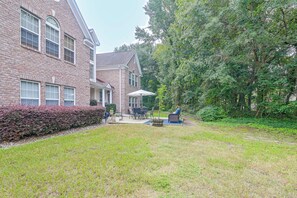 A brick building with a patio area featuring outdoor furniture and a large umbrella. - Murrells Inlet Condo: Close to Beaches, Amenities (Murrells Inlet)