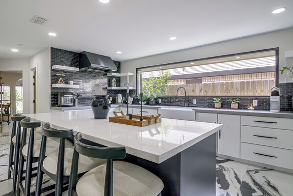 A modern kitchen with a large island, bar stools, and a view of the outdoors. - Near Shopping & Dining! Family Escape in Mcallen (McAllen)