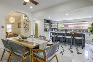 A modern kitchen with a central island, bar stools, and a dining area with a wooden table and wicker chairs. - Near Shopping & Dining! Family Escape in Mcallen (McAllen)