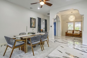 A dining area with a wooden table and chairs, a ceiling fan, and a large window with curtains. - Near Shopping & Dining! Family Escape in Mcallen (McAllen)