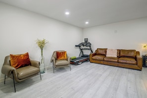 A modern living room with a leather sofa, a leather armchair, a small table with a vase, and a treadmill. - Near Shopping & Dining! Family Escape in Mcallen (McAllen)