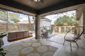 A covered patio area with a wooden bench, two wicker chairs, and a patterned rug. - Near Shopping & Dining! Family Escape in Mcallen (McAllen)