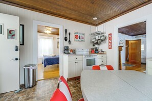 Cocina compacta con comedor, una cama en la habitación contigua y techo de madera.