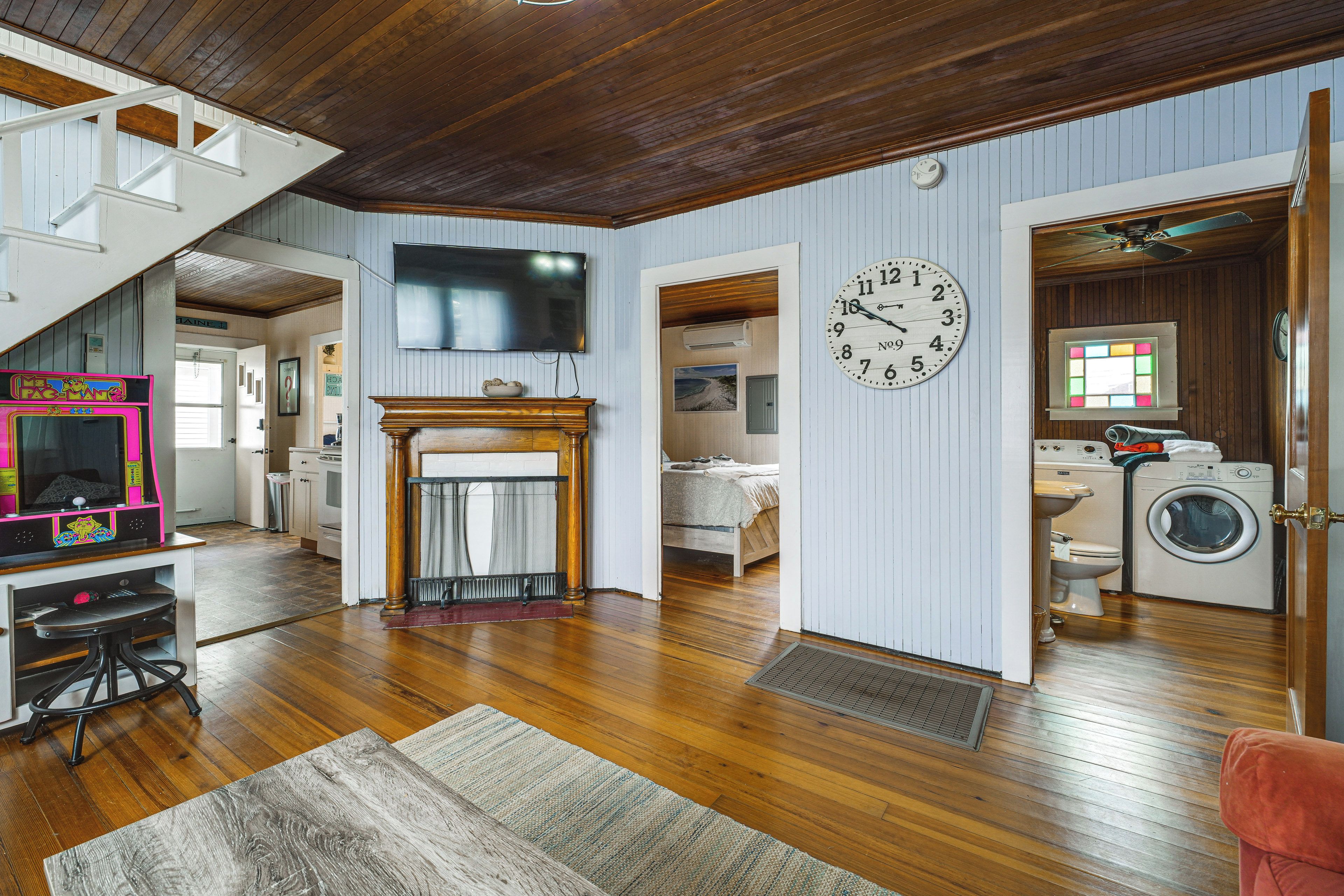 A spacious living room with a fireplace, a television, and a clock on the wall.