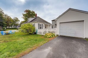 A residential property with a two-car garage, a front porch, and a small lawn area with outdoor furniture. - Steps to Shore! Old Orchard Beach Gem w/ Patio (Old Orchard Beach)