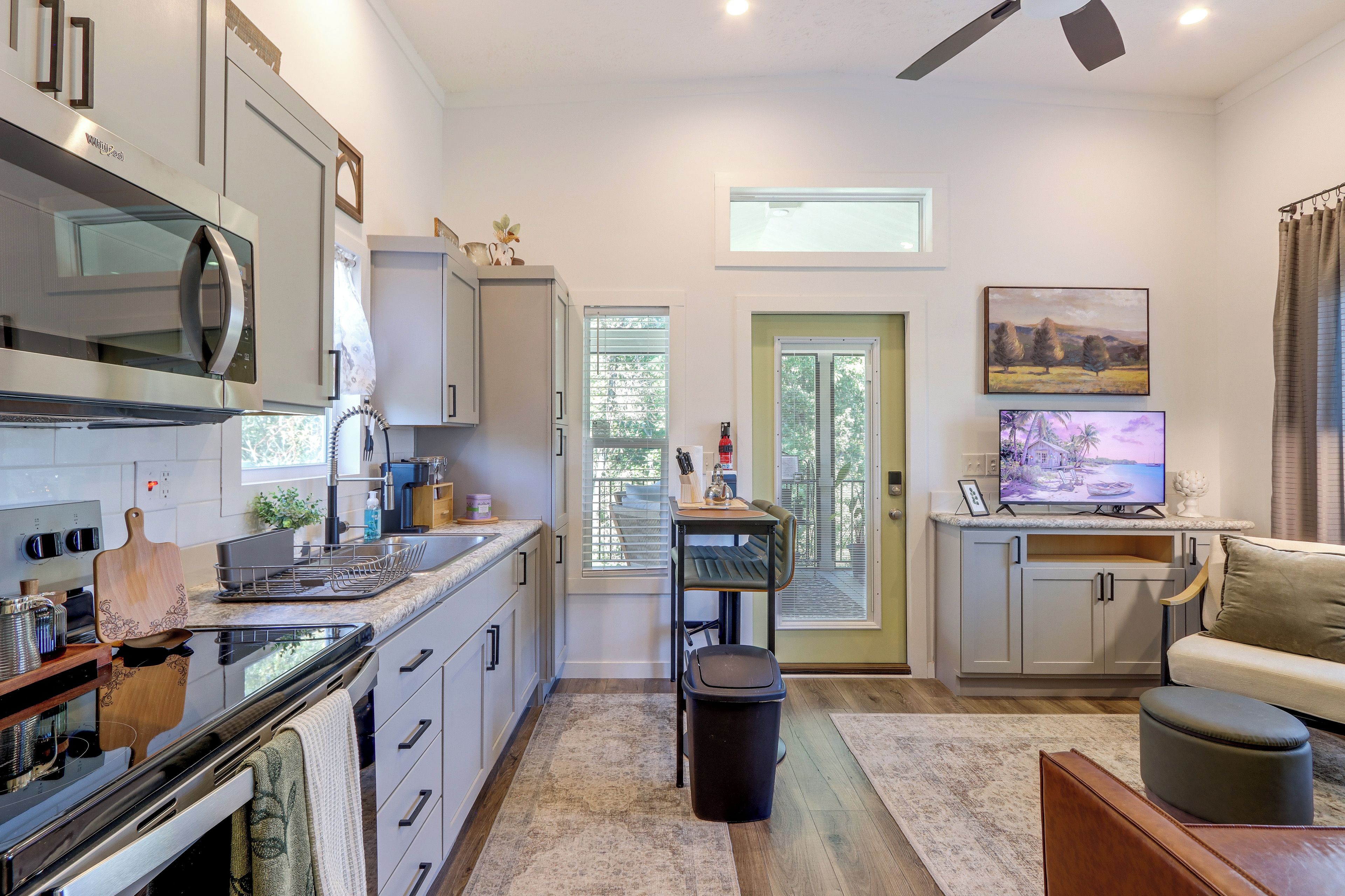 A modern kitchen with a built-in microwave, a dining area with a table and chairs, and a living room with a sofa and a TV.