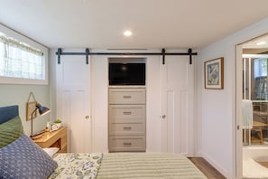A bedroom with a bed, a nightstand, a desk, a sliding closet door, and a window with curtains. - Screened Porch w/ Fireplace! copperhill Tiny Home (Copperhill)