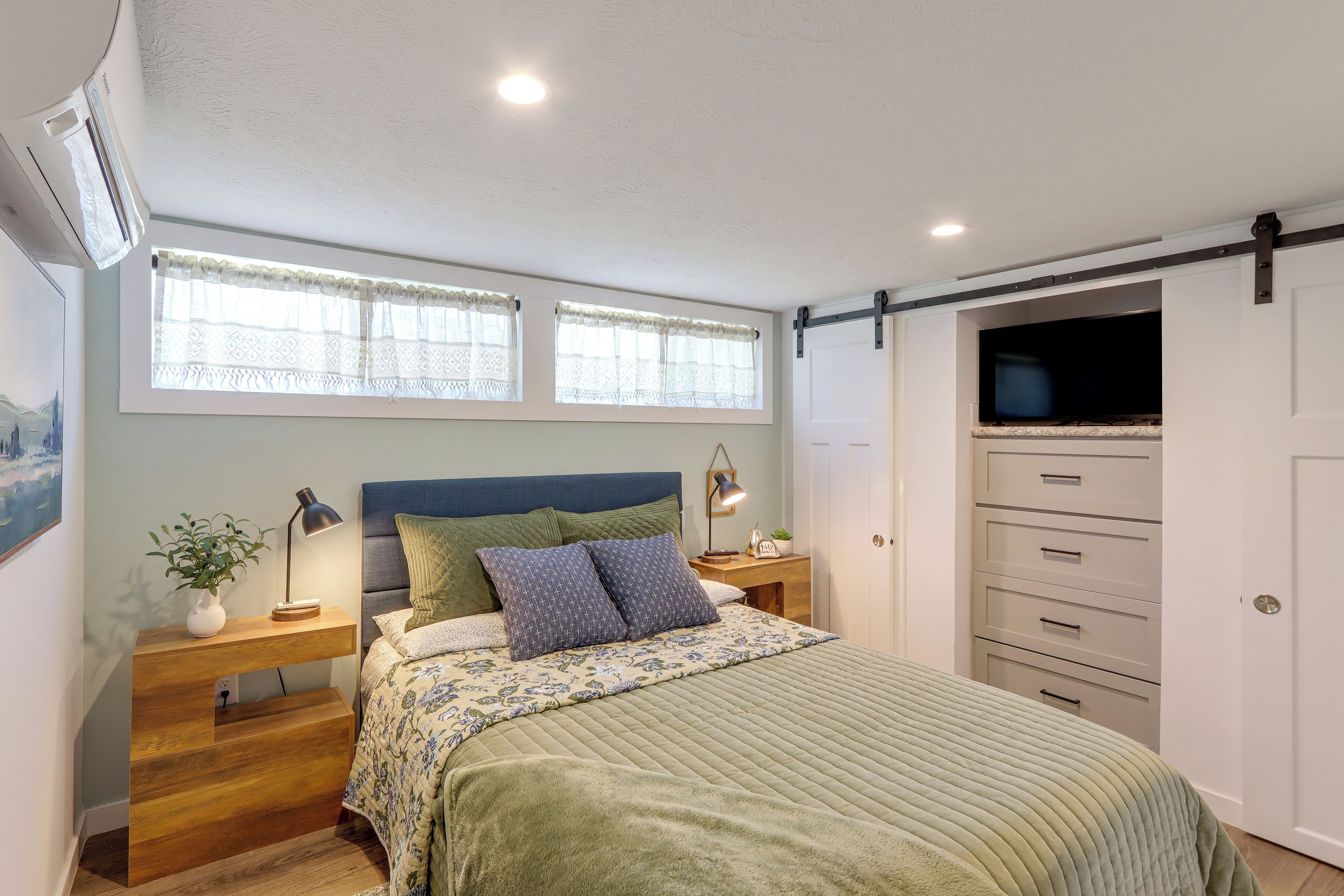 Quarto com cama, mesas de cabeceira, televisão e guarda-roupa.