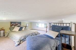 A bedroom with a bed, a blue sofa, and a small table. - Screened Porch w/ Fireplace! copperhill Tiny Home (Copperhill)