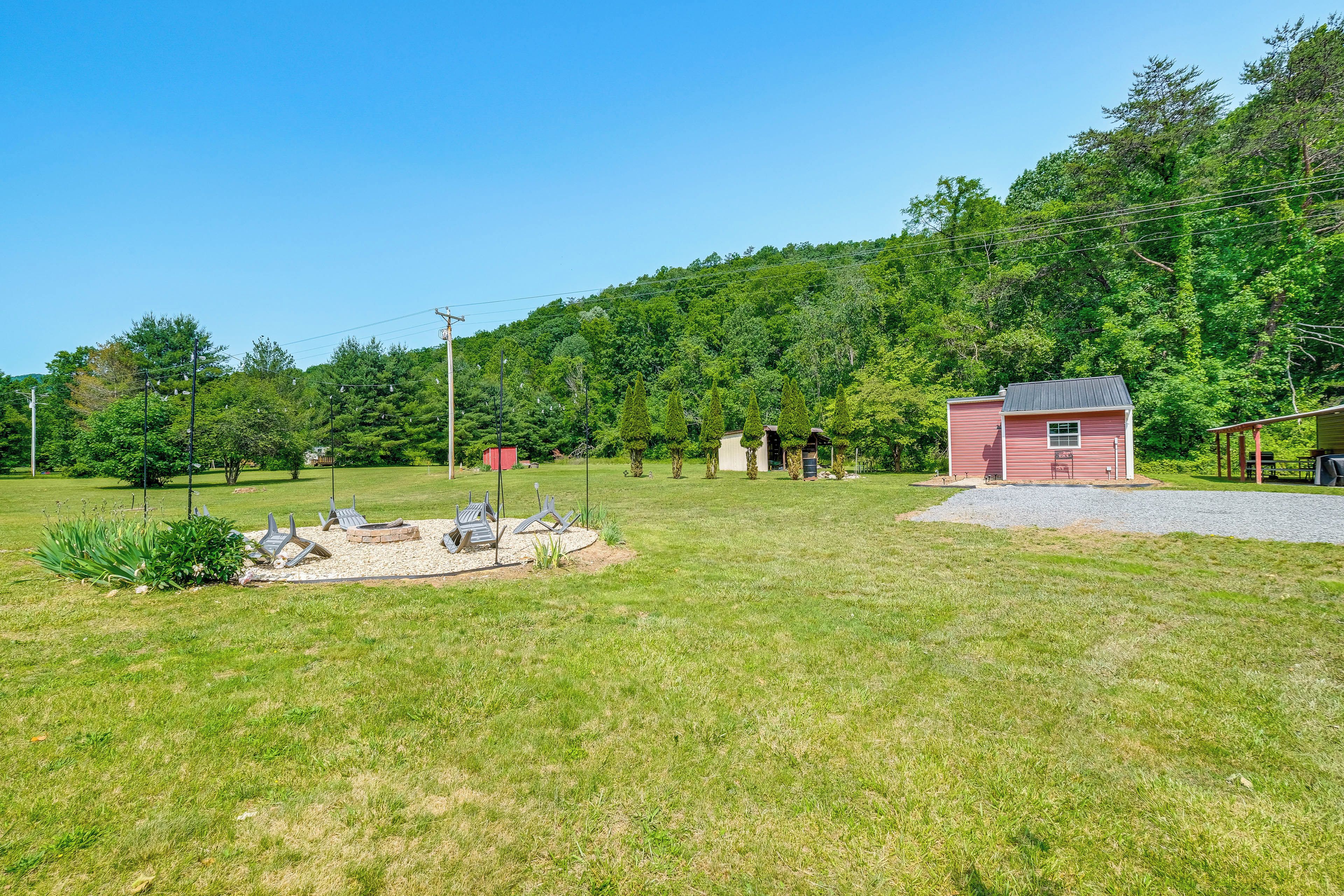 A grassy outdoor area with a small red building, possibly a shed or storage, and a paved path leading to it.