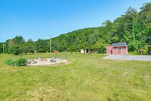 A grassy outdoor area with a small red building, possibly a shed or storage, and a paved path leading to it. - Fall Creek in Covington: 2-unit Retreat (Covington)