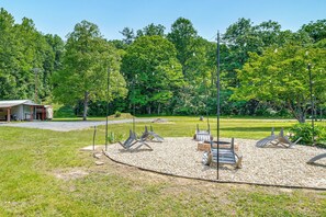 A serene outdoor seating area with multiple chairs and tables, surrounded by a gravel path and lush greenery. - Fall Creek in Covington: 2-unit Retreat (Covington)