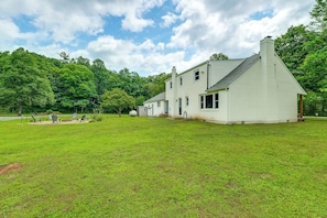 A white two-story house with a sloped roof, surrounded by a well-maintained lawn and trees. - Fall Creek in Covington: 2-unit Retreat (Covington)