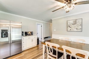 A modern kitchen with stainless steel appliances, a wooden dining table, and a ceiling fan. - Fall Creek in Covington: 2-unit Retreat (Covington)