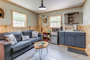 A cozy living room with a grey sofa, a wooden coffee table, and a mounted deer head. - Fall Creek in Covington: 2-unit Retreat (Covington)