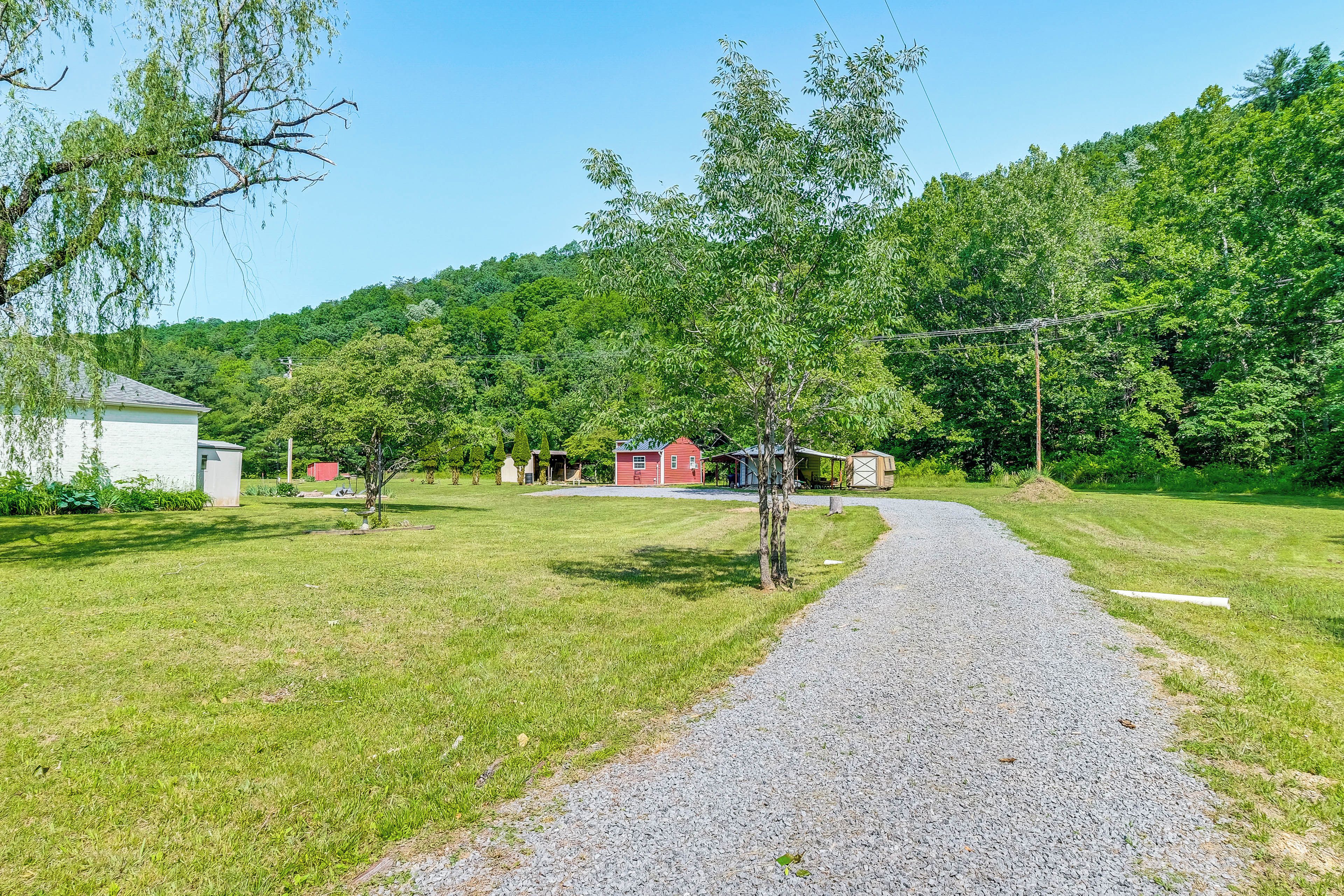 A gravel path leading to a red building surrounded by greenery and trees.