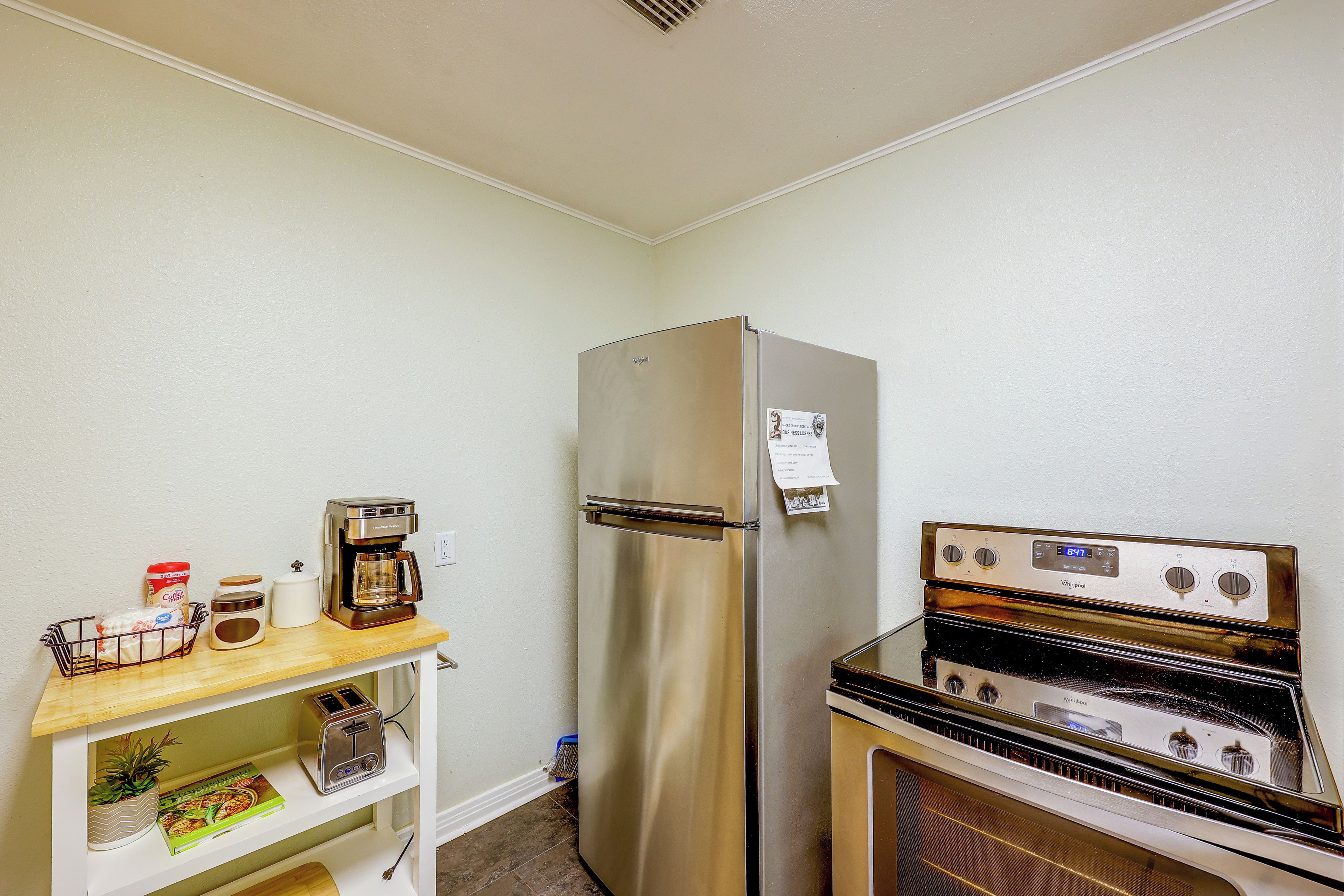 Une petite cuisine équipée d’un réfrigérateur en acier inoxydable, d’une machine à café, d’un grille-pain et d’une cuisinière.