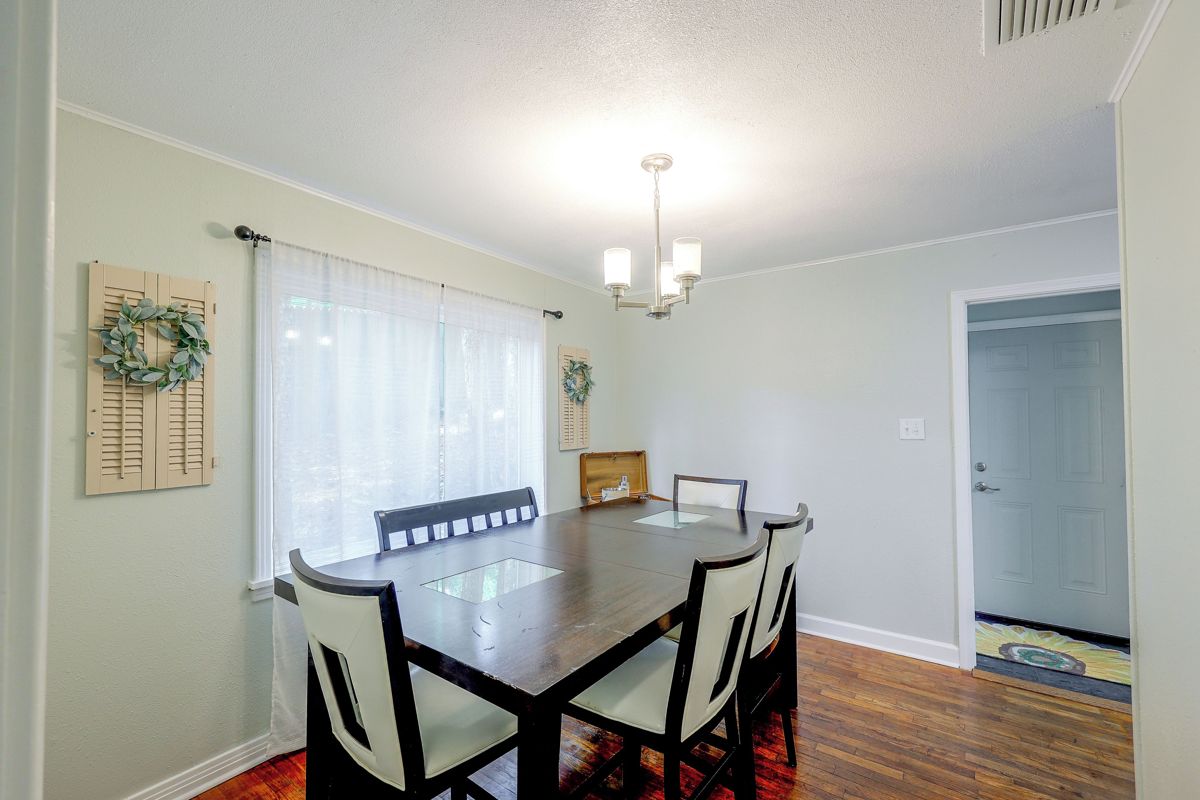 A dining area with a table and chairs, a ceiling light, and a door in the background.