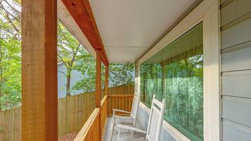 Une véranda couverte avec des balustrades en bois et des chaises blanches.