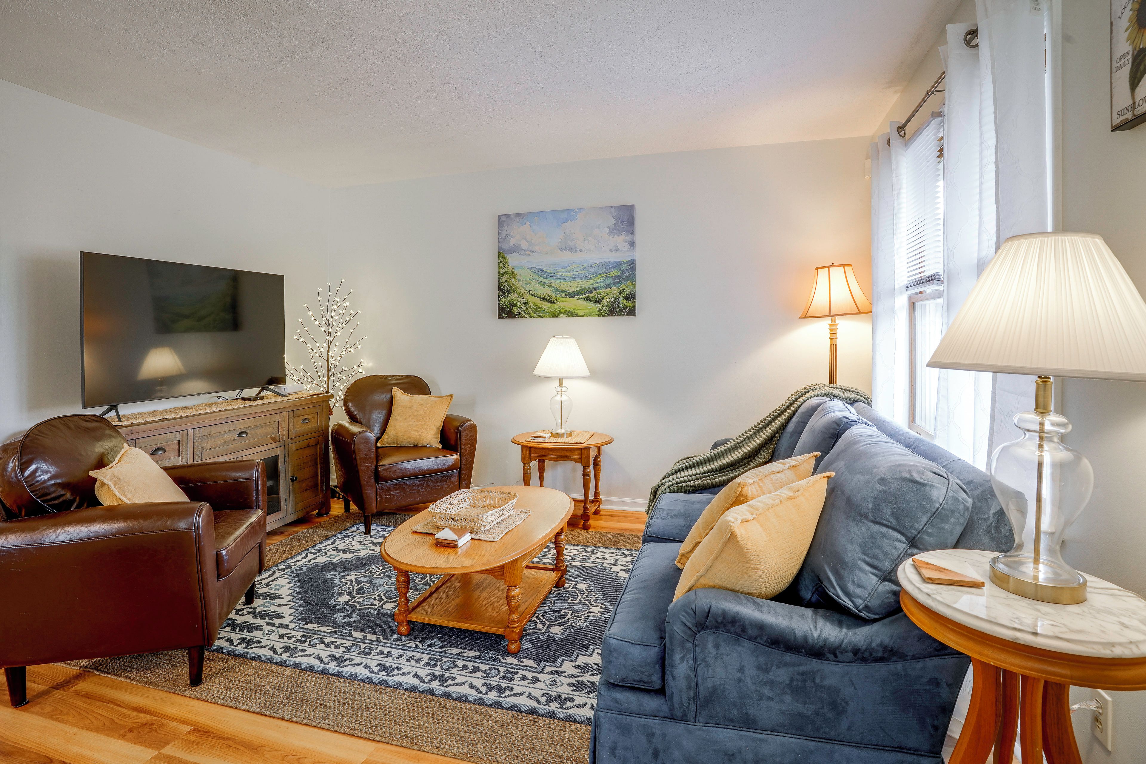 Ein Wohnzimmer mit Sofa, Sesseln, Couchtisch und Fernseher.