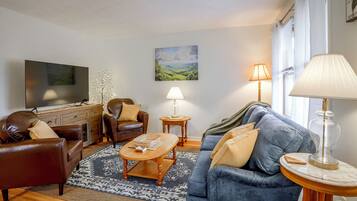 Ein Wohnzimmer mit Sofa, Sesseln, Couchtisch und Fernseher.