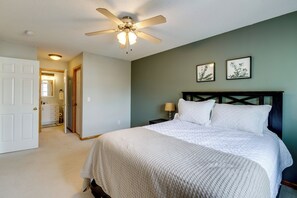 A bedroom with a bed, a ceiling fan, a nightstand, a lamp, and two framed pictures on the wall. - Shakopee Townhome Near Valleyfair & Mystic Lake (Shakopee)