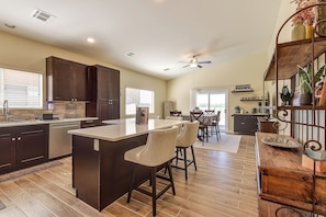 A spacious kitchen with a central island, dark wooden cabinets, and a dining area with a table and chairs. - Tucson Extended Stay Overlooking Kitt Peak (Tucson)