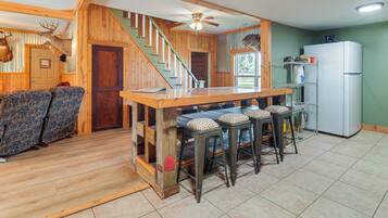A kitchen with a wooden bar, a refrigerator, and a staircase leading to another level.