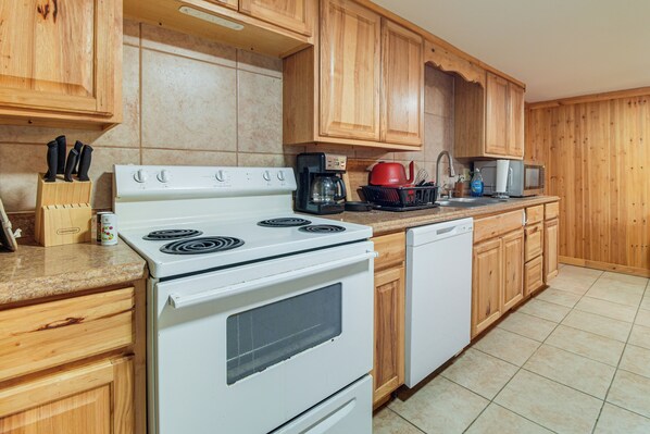 A kitchen with wooden cabinets, a stove, a dishwasher, and a coffee maker.