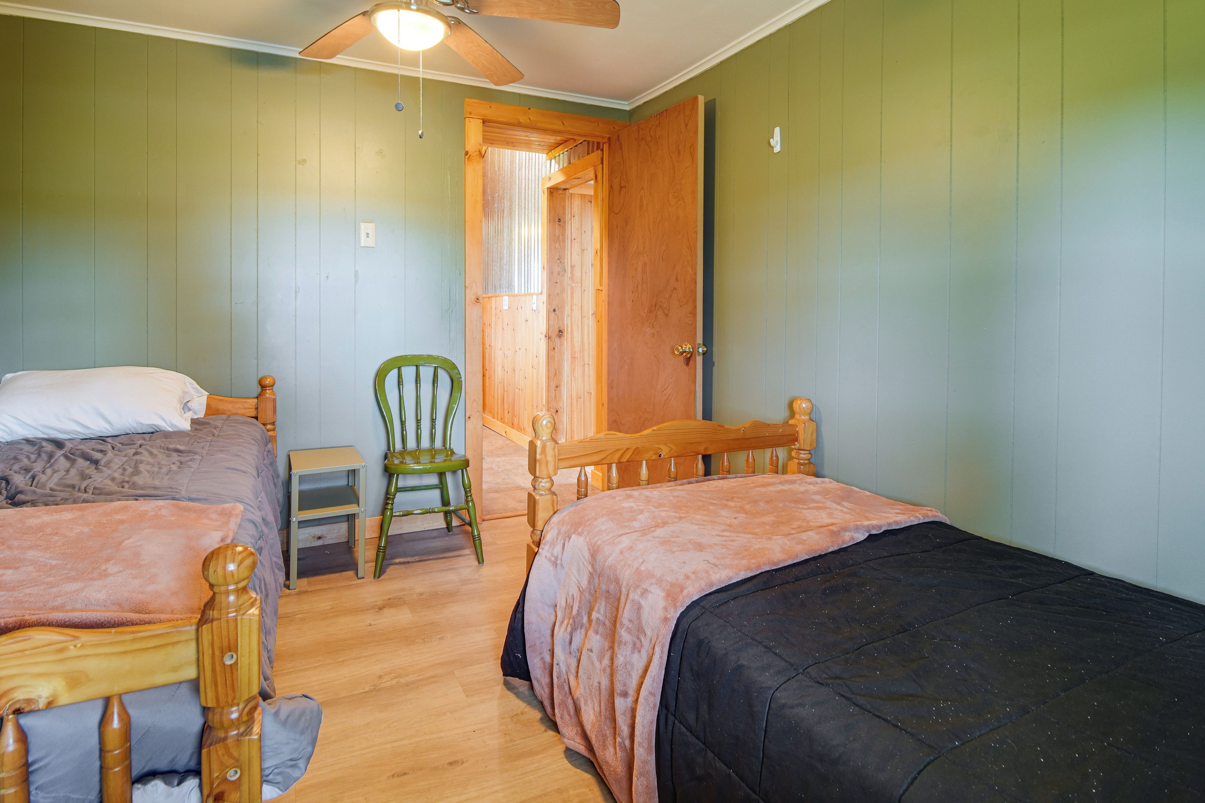 A room with two wooden beds, a chair, and a small table.