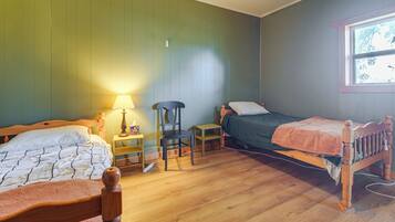 A room with two wooden beds, a chair, a small table, and a window.