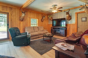 A cozy living room with a fireplace, leather furniture, and mounted deer heads on the wall.