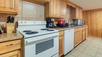 A kitchen with wooden cabinets, a white stove, a dishwasher, and a coffee maker.