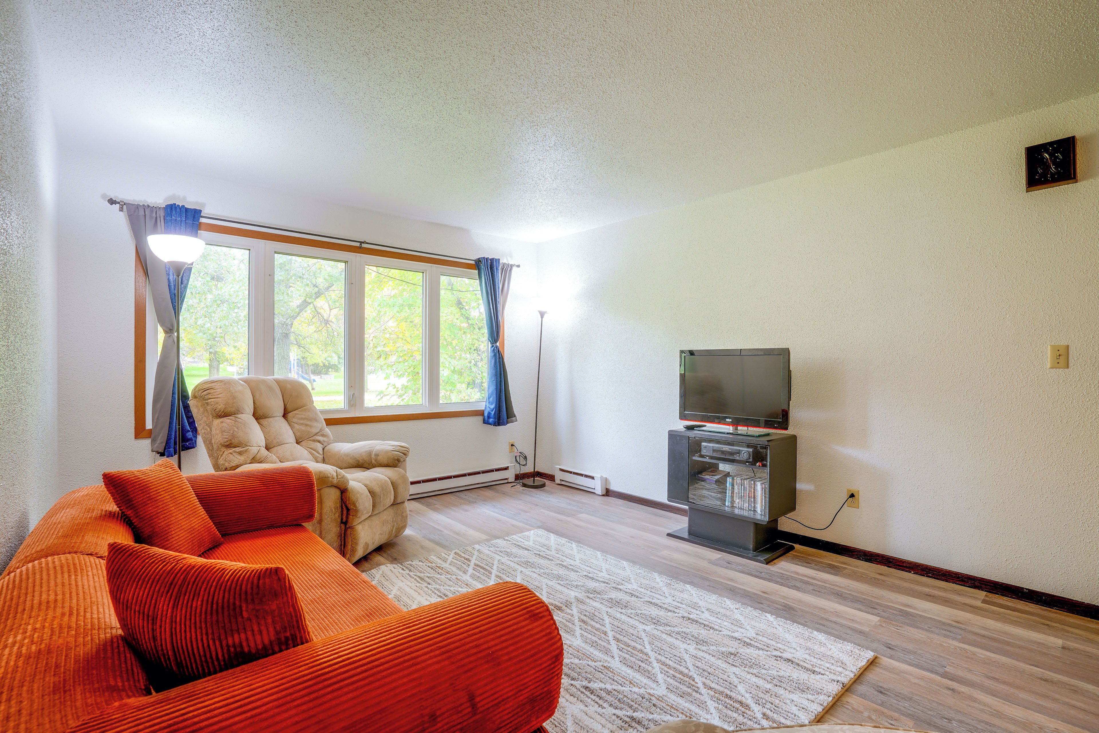 A living room with a sofa, a television, and a window with curtains.
