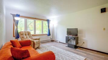 A living room with a sofa, a television, and a window with curtains.