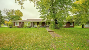 A single-story house with a front porch, a lawn, and a tree in the foreground.