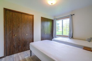 Una habitació amb un llit, una finestra amb cortines i armaris de fusta.