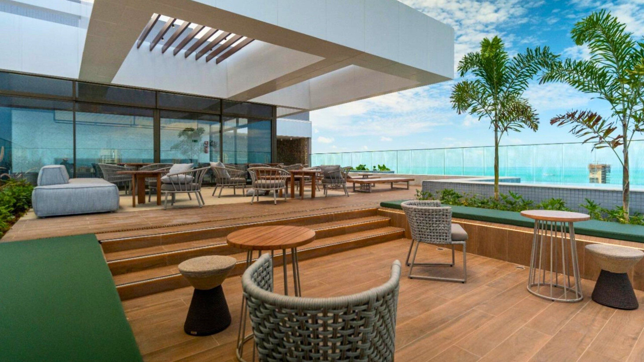 Une terrasse sur le toit avec des sièges extérieurs, une piscine et une vue sur l’océan.