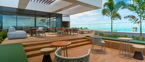 A rooftop terrace with outdoor seating, a pool, and a view of the ocean.