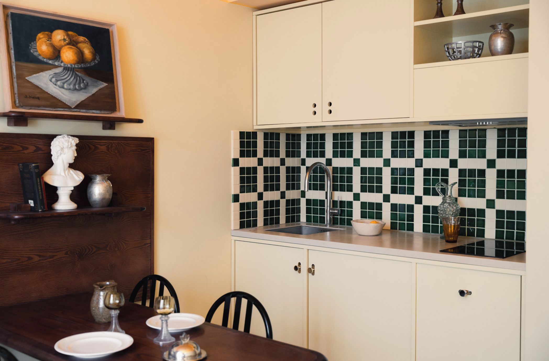 Una cucina con zoccolo in piastrelle, un tavolo da pranzo con sedie e un quadro sopra il tavolo.