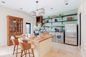 A modern kitchen with a central island, bar stools, a built-in oven, and a refrigerator. - The Lincoln Retreat | 3 Blocks to Forsyth | Shops (Savannah)