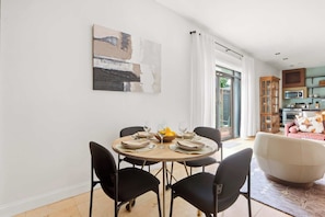 A dining area with a round table, black chairs, and a bowl of fruit. - The Lincoln Retreat | 3 Blocks to Forsyth | Shops (Savannah)