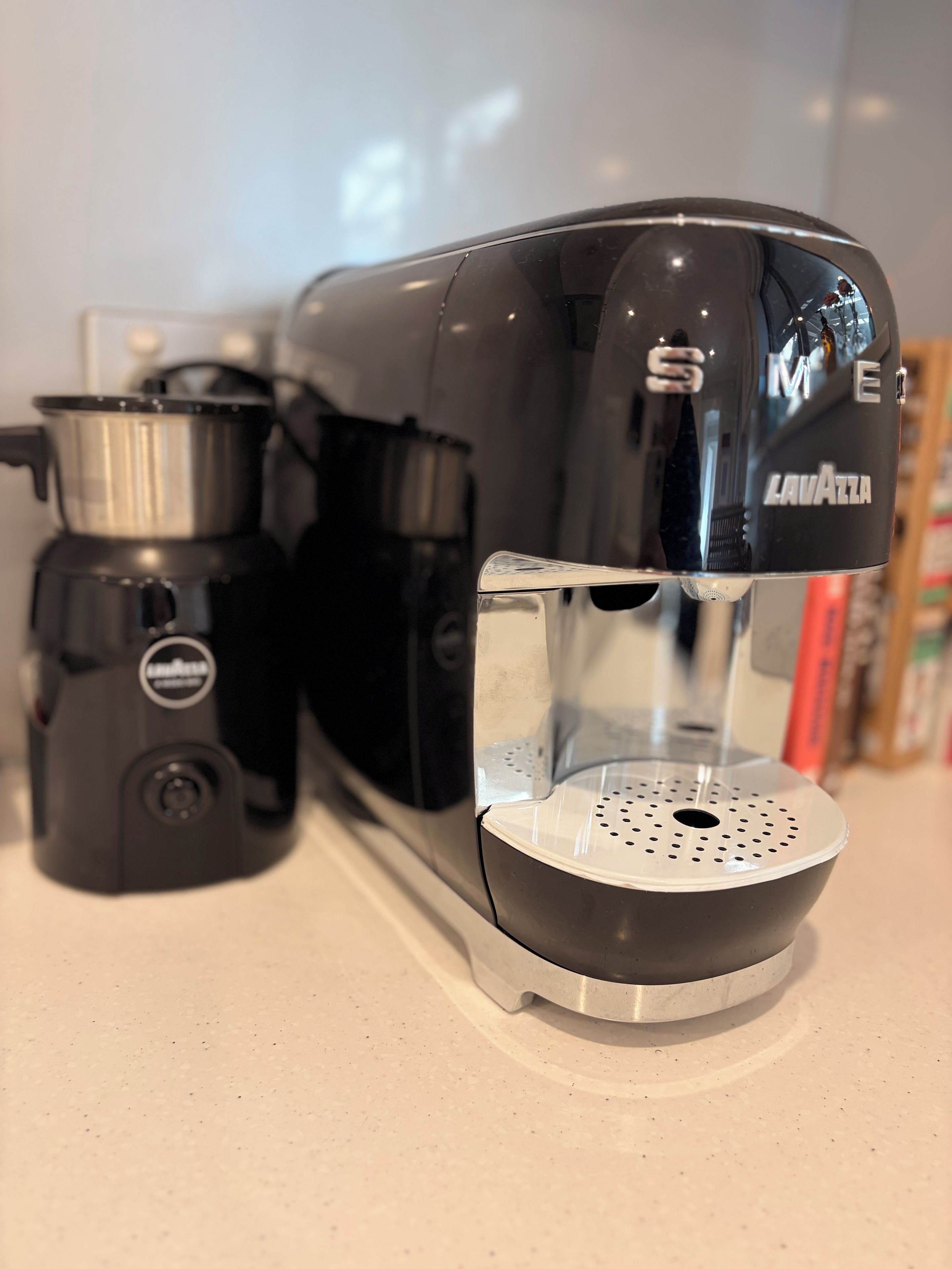 A coffee machine with a transparent water reservoir and a drip tray.