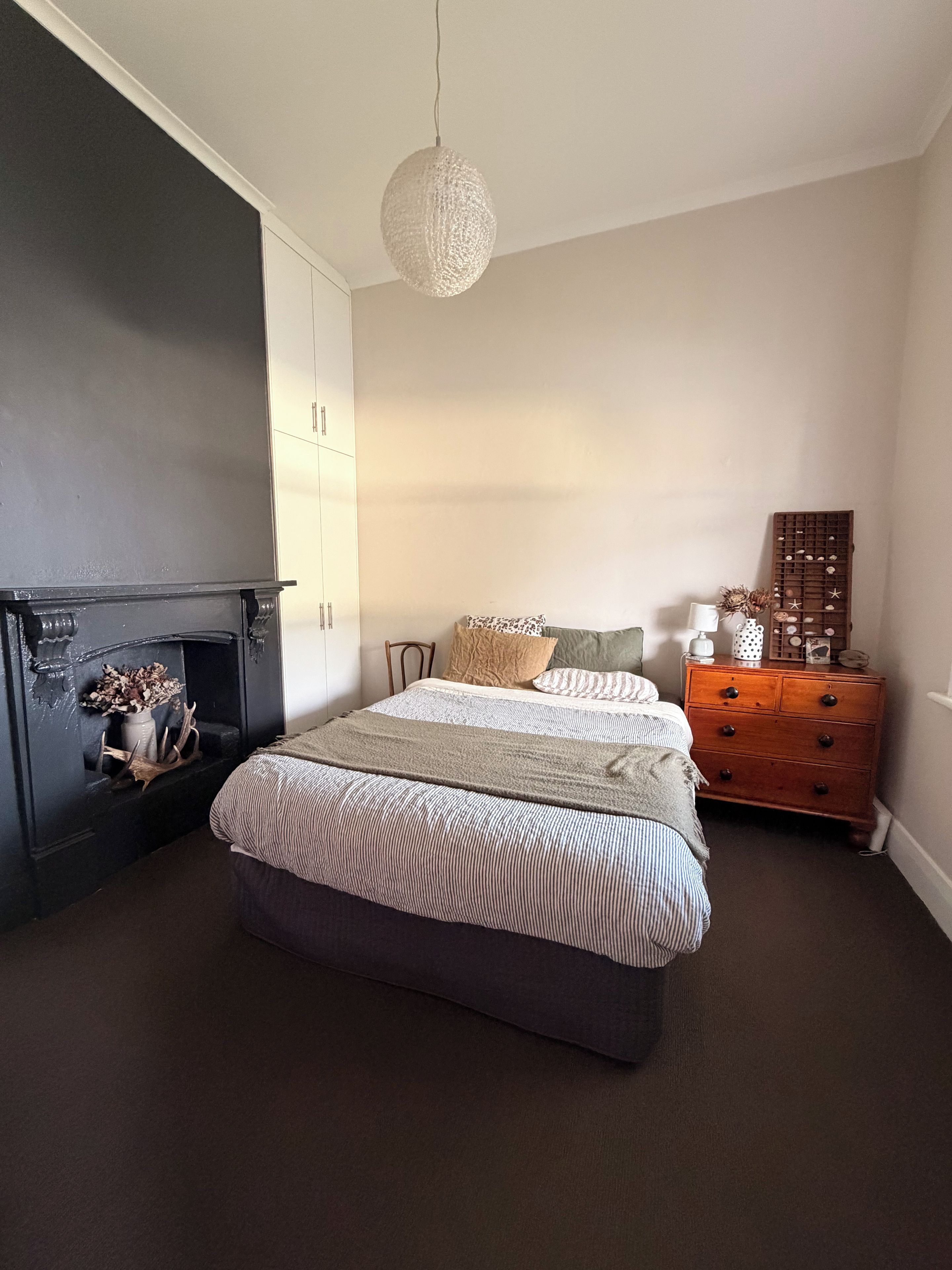 Ein Schlafzimmer mit Bett, Kommode und Kamin.
