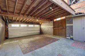 A garage with a concrete floor, wooden beams, and a metal garage door. - Sleep 12 | 2 Garages | Pets | Steps to Broughton (Savannah)
