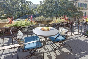 A deck with a round table and two chairs, a glass of red wine, and a plate of food. - Sleep 12 | 2 Garages | Pets | Steps to Broughton (Savannah)