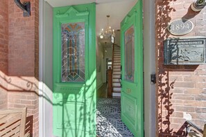 A green door with a stained glass window, a staircase, and a plaque on the wall. - Sleep 12 | 2 Garages | Pets | Steps to Broughton (Savannah)
