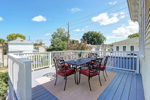 A covered outdoor patio with a table and chairs, surrounded by a white railing. - The Upper Olmstead - 1800s Victorian Near Forsyth (Savannah)