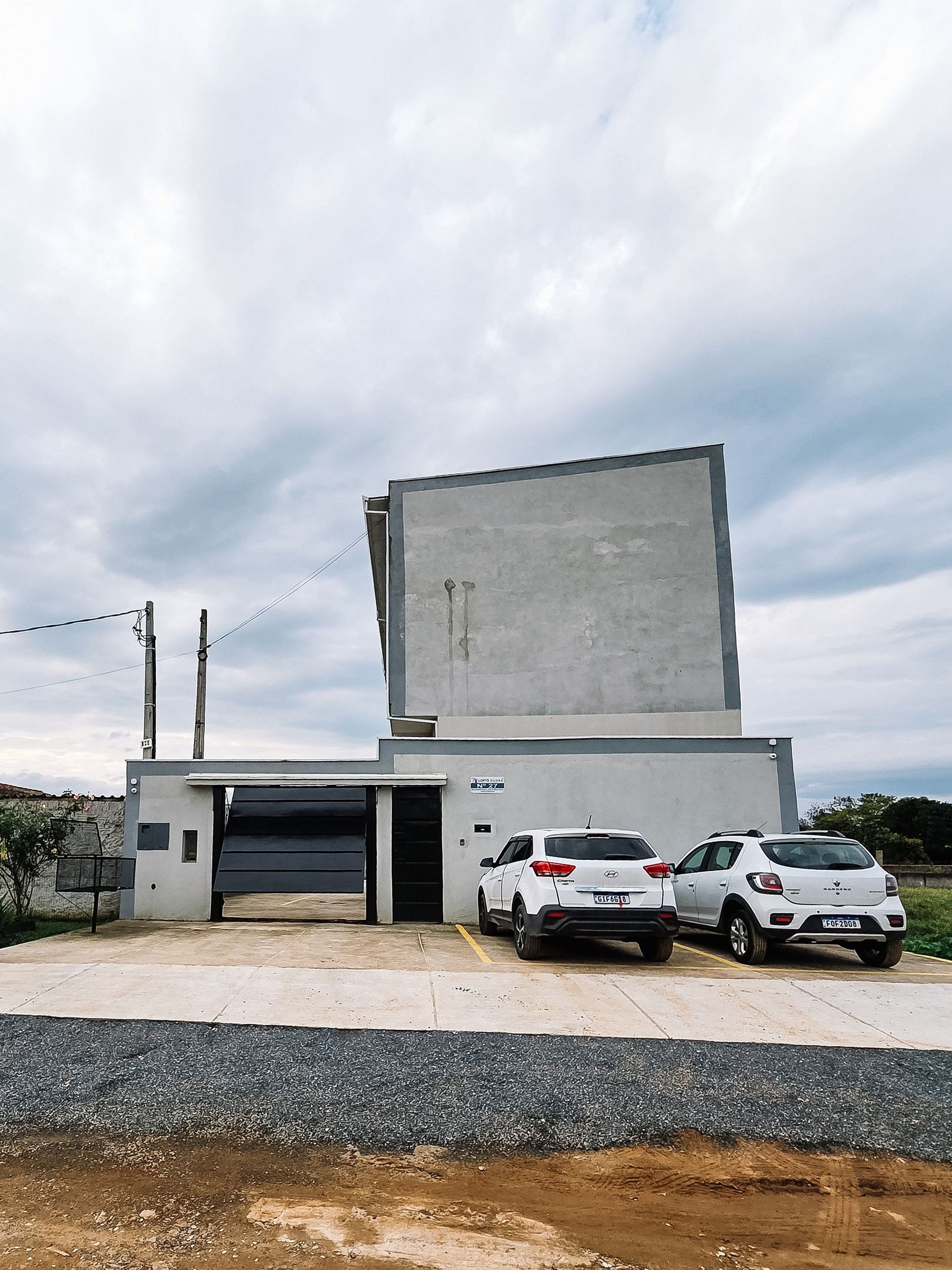 A modern building with a garage and two parked cars.